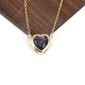 Dettaglio del ciondolo a cuore con zircone viola e catena dorata su fondo in legno - Viola