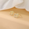 Minimalist geometric square earrings in gold with zircon stones on a beige background - Gold