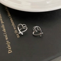 Minimalist silver hollow heart stud earrings set on a black book background - Silver Heart Ear Bone Clip