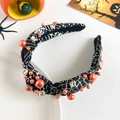 Detail of black spider web headband with orange pearls and rhinestones on white plate - Halloween Knot Headband - Black Spider Web with Pearls