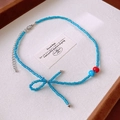 Blue beaded necklace with bow design and red accents on a cream jewelry tray - 25# Necklace - Blue Red Bowknot