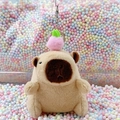Plush capybara keychain featuring a pink peach decoration on a colorful foam background - Light Brown Peach + Silver Clip