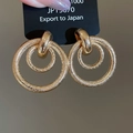 Detail van gouden dubbele cirkel oorbellen met een fijne matte gehamerde textuur - In elkaar grijpende dubbele cirkel (Goud)