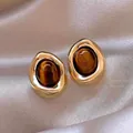 Detail von 18K vergoldeten Ohrringen mit ovalem Tigerauge auf Seidenstoff platziert - Vintage Goldbraun Rund (Stil 4 Silbernadel)
