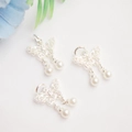 Detailed view of silver bow pendants with white pearls on a soft white fabric background - Silver / White Zirconia