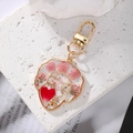 Macro detail of epoxy resin keychain with gold wire face outline and dried pink flowers - Pink Three Flowers