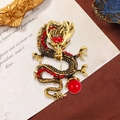 Golden dragon brooch with red crystals and a round red bead on a vintage paper background - Red Rhinestone