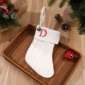 White knitted Christmas stocking with red embroidered letter D and holly leaf detail - Letter D