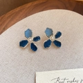 Close-up of denim flower earrings with silver edges and white pearl centers on fabric - Blue-Denim Flower-Pearl