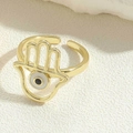 Macro detail of golden Hamsa Hand ring with blue Evil Eye inlay on open band - Grey Hamsa Hand