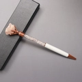 Detail of a white metal pen with pink crystal fragments and raw stone top in a gift box - Rose Quartz
