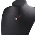Macro detail of rose gold puzzle piece pendant on black mannequin with polished finish - Rose Gold