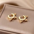 Close-up of golden beaded hoop earrings with geometric stud details on a satin box - Gold Ball