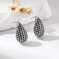 Detail view of silver drop earrings with black pavé stones on elegant white fabric background - Black