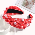 Close-up of a red knotted headband with pink faux pearls on a white cup and saucer - Red Star Heart