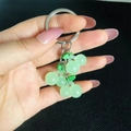 Detailed close-up of a green resin cherry keychain with a luminous transparent finish - Green