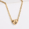 Nahaufnahme von goldenem Herzanhänger mit schwarzem Buchstaben D an einer Metallkette - Buchstabe D