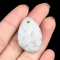 Hand holding a white howlite teardrop stone pendant with natural grey marble patterns - Howlite
