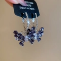 Gros plan sur des créoles en argent 925 avec pendentifs papillons en zircon violet - Papillon Violet