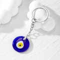 Makroaufnahme von blauem Evil Eye Glasanhänger auf weißem Wolken-Dekorationshintergrund - Königsblau Gelbes Auge