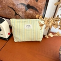 Dettaglio ravvicinato della trousse in tela a righe gialle e blu su un tavolo di legno - Giallo (Riga Verticale)