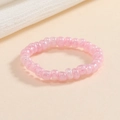 Dettaglio dell'anello elastico con perline rosa lucide su uno sfondo beige neutro - Rosa Chiaro