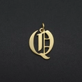 Detail of gothic letter Q pendant in gold finish over a textured black background - Letter Q