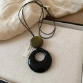 Macro detail of irregular hollow black pendant and green bead on a leather cord necklace - 10# Black Green Flat Round