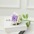 Detail einer handgefertigten Häkelrose in Lila und Creme mit grünen Blättern aus Wolle - Mengsi Lila