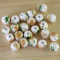 Macro shot of white ceramic beads with yellow floral patterns on light wood background - No.39-Yellow Flowers Green Leaves