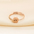 Detail of rose gold cat paw ring with open design on elegant silk fabric background - US 6