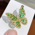 Close-up of golden butterfly ring with green gems and white crystals on a card - Gold Green Zirconia