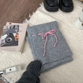 Folded grey knitted bottom featuring a contrasting pink drawstring on beige rug - Scarf / Gray