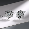Macro shot of silver snowflake earrings with black enamel and sparkling white zircon studs - White Gold