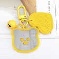 Cute yellow bear keychain with mirror face, heart charm and bell on white table - Yellow