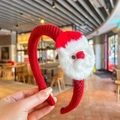 Gros plan sur un serre-tête de Noël tricoté rouge avec décoration Père Noël en peluche - Serre-tête Père Noël en feutre