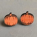 Macro view of handmade wooden pumpkin earrings with orange finish and black outlines - Pumpkin