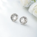 Elegantes pendientes redondos plateados con circonitas incrustadas sobre fondo de flores blancas - Chapado en blanco