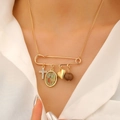 Close-up of gold safety pin pendant with religious icons and heart charm necklace - 04 KC Gold (0142)