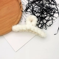 Detailopname van een witte pluche haarklem op een rustiek houten dienblad met textuur - 1# Crèmewit