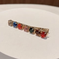 Dettaglio di un fermaglio per capelli dorato con sette strass colorati e brillanti - Rotondo / Tondo Colore Misto B