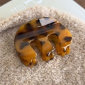 Close-up of tortoise shell pattern acrylic hair claw clip on soft beige plush fabric - Tortoise