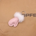 Dettaglio portachiavi a cuore in pelle rosa con pompon bianco su carta kraft - Rosa