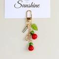 Close-up of a cherry keychain with red beads, green leaf, and gold D-ring clasp - Red Cherry Beads