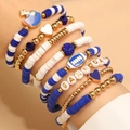 Vista macro di braccialetti impilati Game Day con perline heishi blu e ciondoli football - KC Oro Blu Bianco (S604)