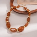 Close-up of brown acrylic pebble beads and gold metal spacers on a vintage sweater chain - Dark Coffee