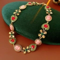 Detalle macro de un collar vintage dorado con corazones de esmalte e incrustaciones - Collar (Dorado-Verde)