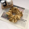 Lustrous gold velvet oversized scrunchie placed on vintage newspaper background - Yellow