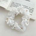Elegant white mesh scrunchie with golden stars detail on an open book background - FQ1068B White Star Scrunchie
