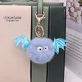 Detailed view of plush blue bat keychain with fur pompom on a stylish bag strap - Gold Chain / Light Blue